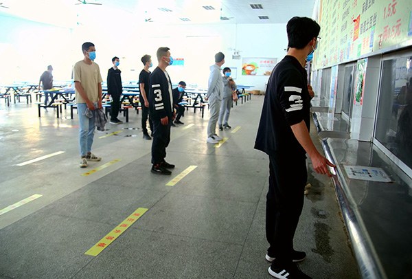 学生佩戴口罩，前后间隔1.5米排队领餐.jpg